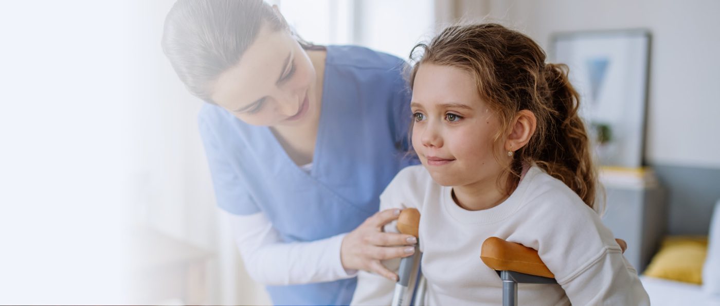 Young nurse helping to walk to little girl with broken leg.